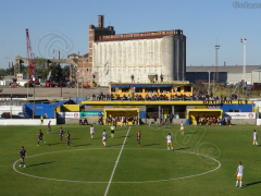 Blick aufs Spielfeld und Hafengelände beim Spiel Dock Sud gegen Colegiales im Estadio de los Inmigrantes, April 2022